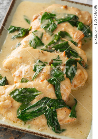 Creamy Chicken Florentine tender pan-fried chicken coated in an amazing garlic spinach white wine cream sauce close-up on a plate. Vertical 135756096
