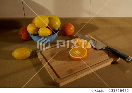 Fresh Citrus Fruits on Cutting Board With Knife and Bowl of Lemons and Oranges 135756486