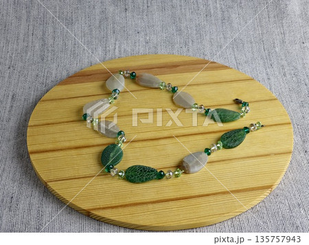 Handcrafted beads made of natural green and matte white agate with a crackle effect on a wooden board background Handcrafted beads made of natural green and matte white agate with a crackle effect on a wooden board background 135757943