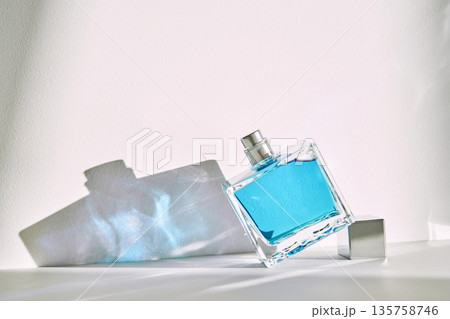 Perfume bottle with blue liquid creating shadows 135758746