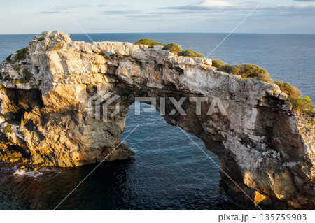 Es Pontas rock on Mallorca, Spain. Natural stone bridge between Cala Santanyi and Cala Llombards during the sunset close up Es Pontas rock on Mallorca, Spain. Natural stone bridge between Cala Santanyi and Cala Llombards during the sunset close up 135759903