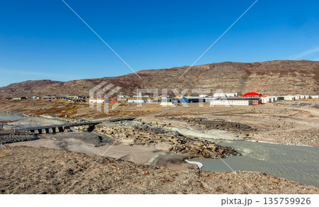 Inland arctic greenlandic settlement with river, bridge and scattered buildings surrounded by rocky terrain and dry tundra landscape in Kangerlussuaq, Greenland Inland arctic greenlandic settlement with river, bridge and scattered buildings surrounded by rocky terrain and dry tundra landscape in Kangerlussuaq, Greenland 135759926
