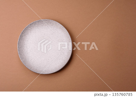 An empty round ceramic plate on a table, kitchenware. An empty plate 135760785