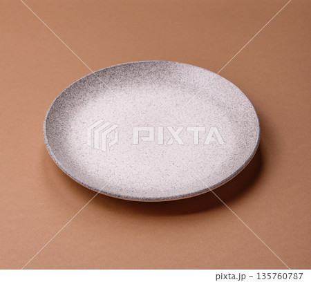 An empty round ceramic plate on a table, kitchenware. An empty plate An empty round ceramic plate on a table, kitchenware. An empty plate 135760787