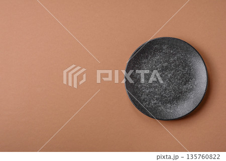 An empty round ceramic plate on a table, kitchenware. An empty plate An empty round ceramic plate on a table, kitchenware. An empty plate 135760822