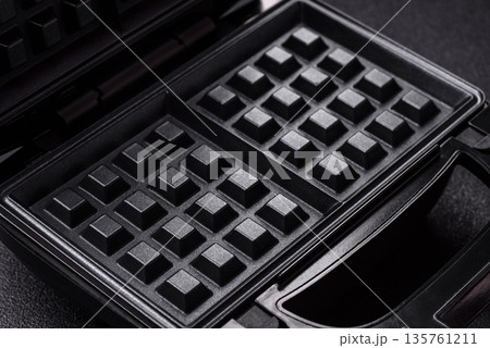 A waffle iron, an electric machine for making Belgian breakfast desserts. A waffle iron 135761211