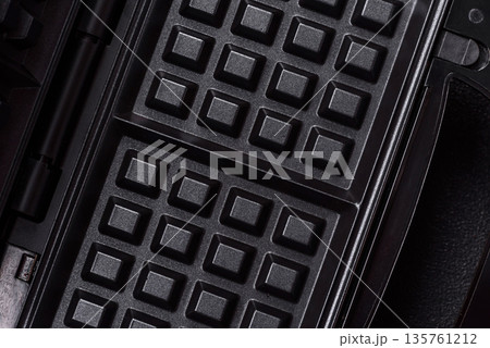 A waffle iron, an electric machine for making Belgian breakfast desserts. A waffle iron 135761212
