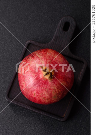 A juicy, ripe, whole red pomegranate as a source of beneficial nutrients. A whole red pomegranate 135761329