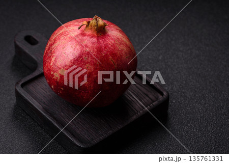 A juicy, ripe, whole red pomegranate as a source of beneficial nutrients. A whole red pomegranate 135761331