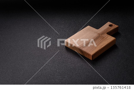 Wood, a wooden empty cutting board on a dark kitchen table. Wooden cutting board 135761418