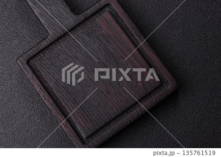 Wood, a wooden empty cutting board on a dark kitchen table. Wooden cutting board Wood, a wooden empty cutting board on a dark kitchen table. Wooden cutting board 135761519