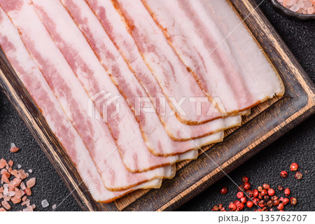 Raw smoked bacon slices, ham, jamon, or prosciutto strips for cooking. Raw bacon slices 135762707