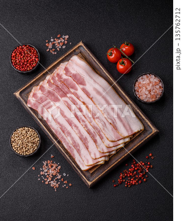Raw smoked bacon slices, ham, jamon, or prosciutto strips for cooking. Raw bacon slices Raw smoked bacon slices, ham, jamon, or prosciutto strips for cooking. Raw bacon slices 135762712