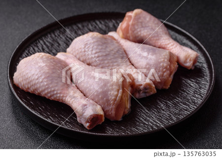 Chicken meat, raw drumsticks on the bone for grilling with salt and spices. Raw chicken drumsticks Chicken meat, raw drumsticks on the bone for grilling with salt and spices. Raw chicken drumsticks 135763035