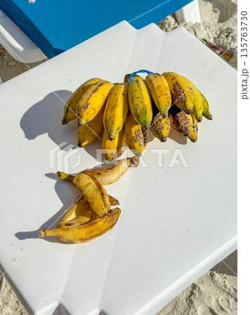 Ripe Bananas On White Plastic Table In Tropical Beach Sunlight Ripe Bananas On White Plastic Table In Tropical Beach Sunlight 135763730