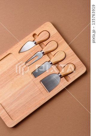 A set of cheese knives with a wooden cutting board, slicing tools. Cheese knives 135763919