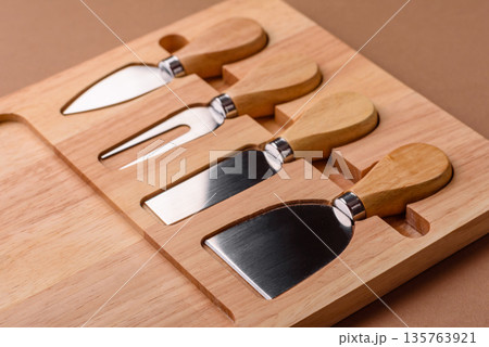A set of cheese knives with a wooden cutting board, slicing tools. Cheese knives 135763921