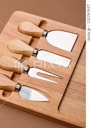 A set of cheese knives with a wooden cutting board, slicing tools. Cheese knives A set of cheese knives with a wooden cutting board, slicing tools. Cheese knives 135763927