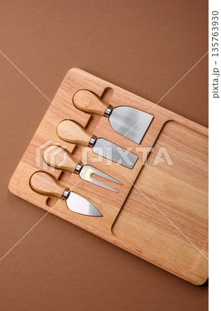A set of cheese knives with a wooden cutting board, slicing tools. Cheese knives A set of cheese knives with a wooden cutting board, slicing tools. Cheese knives 135763930