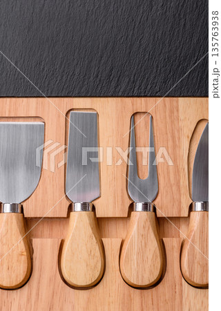 A set of cheese knives with a wooden cutting board, slicing tools. Cheese knives A set of cheese knives with a wooden cutting board, slicing tools. Cheese knives 135763938