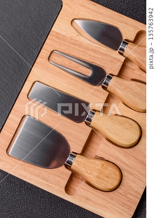 A set of cheese knives with a wooden cutting board, slicing tools. Cheese knives 135763942