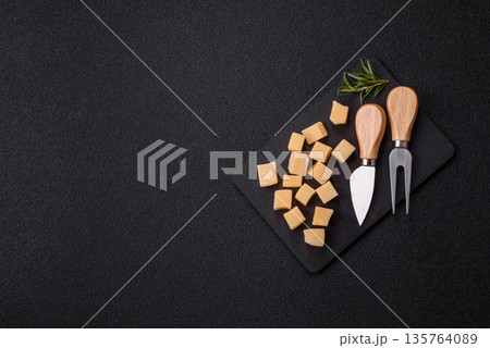 Cubed cheddar, gouda, or parmesan cheese on a cutting board. Cubed cheese 135764089