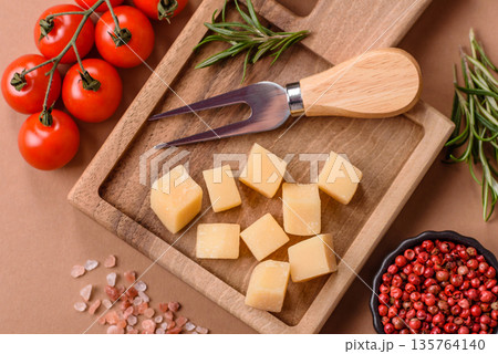 Cubed cheddar, gouda, or parmesan cheese on a cutting board. Cubed cheese 135764140