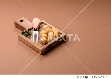 Cubed cheddar, gouda, or parmesan cheese on a cutting board. Cubed cheese Cubed cheddar, gouda, or parmesan cheese on a cutting board. Cubed cheese 135764147