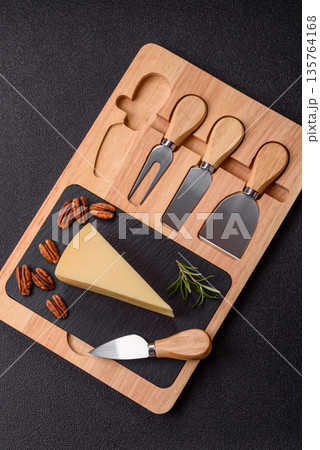 A wedge of cheddar, gouda, or parmesan cheese on a cutting board. Cheese wedge 135764168