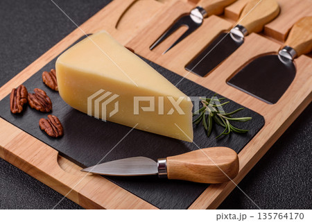 A wedge of cheddar, gouda, or parmesan cheese on a cutting board. Cheese wedge 135764170