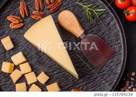A wedge of cheddar, gouda, or parmesan cheese on a cutting board. Cheese wedge 135764238