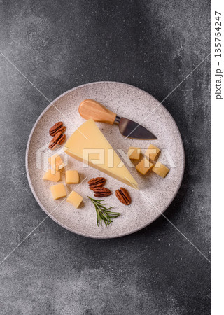 A wedge of cheddar, gouda, or parmesan cheese on a cutting board. Cheese wedge 135764247