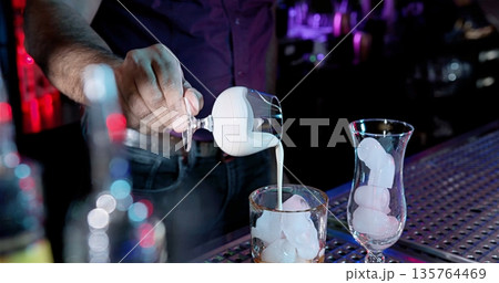 Ambiently Lit Nightclub Where Bartender Meticulously Pours Cream Into Glasses For Cocktails Ambiently Lit Nightclub Where Bartender Meticulously Pours Cream Into Glasses For Cocktails 135764469