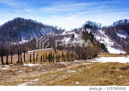 rural landscape of carpathian mountains in early spring under blue sky. snow covered hill with barbed wire fence on a sunny day. green environment sustainability and protection. background for earth rural landscape of carpathian mountains in early spring under blue sky. snow covered hill with barbed wire fence on a sunny day. green environment sustainability and protection. background for earth 135765088