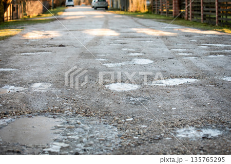 Icy Rural Road With Frozen Puddles Creating Slippery Winter Driving Conditions 135765295