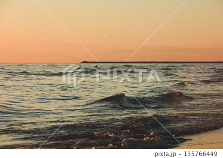 Vlora, Albania  August , 2025 Sunset reflections on the shoreline as gentle waves wash over the sand, capturing warm golden light and peaceful evening scenery on the Adriatic coast. 135766449