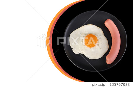 Fried egg and sausage on a black plate, on a black background, place under the text on a white background Fried egg and sausage on a black plate, on a black background, place under the text on a white background 135767088