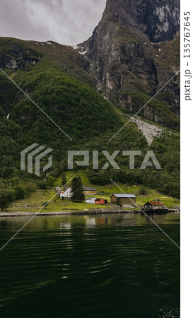 A mountain with waterfall and houses in the background Houses are on the right side of the waterfall 135767645