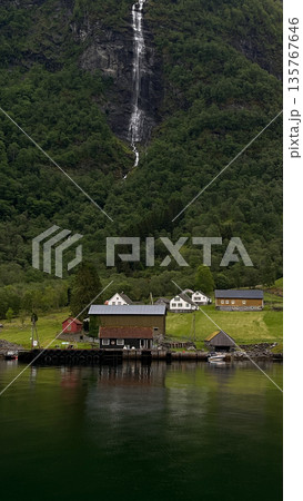 A mountain with waterfall and houses in the background Houses are on the right side of the waterfall A mountain with waterfall and houses in the background Houses are on the right side of the waterfall 135767646