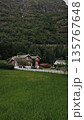 Red house in mountains. Green hills, clear sky, peaceful Nordic landscape.  135767648