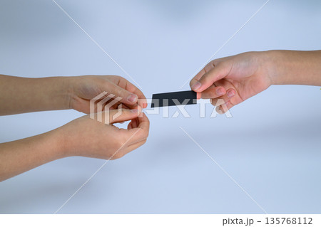 二人の手で交わされる黒い無地のミニカード 135768112