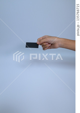 黒いミニカードを持つ手と下部の広い余白 135768715