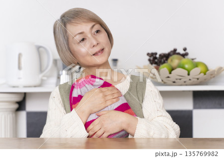 キッチンで湯たんぽにお湯を注ぐシニア女性 キッチンで湯たんぽにお湯を注ぐシニア女性 135769982