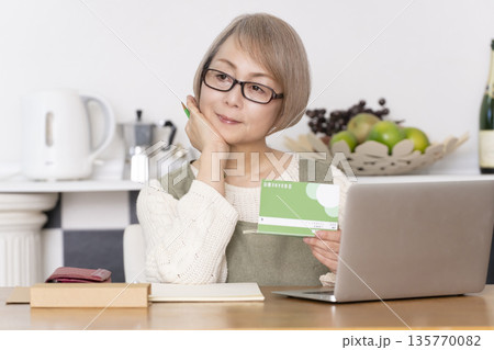 キッチンで家計簿をつけるシニア女性 135770082