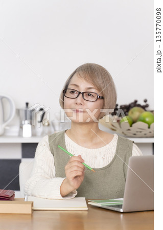 キッチンで家計簿をつけるシニア女性 キッチンで家計簿をつけるシニア女性 135770098