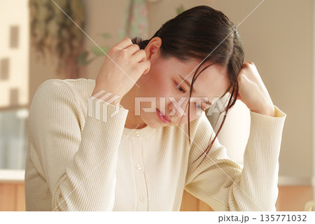 不安な表情で頭を抱える若い女性 135771032