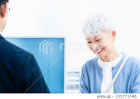 窓口で手続きをするシニア女性 135771340