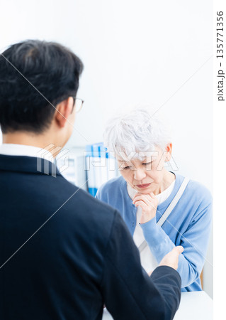 窓口で手続きをするシニア女性 135771356