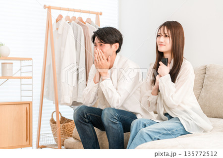 家のリビングでソファーでテレビを見る若いアジア人夫婦,カップル（感動,涙,涙活） 135772512