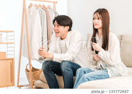 リビングでテレビ観戦する若いアジア人カップル リビングでテレビ観戦する若いアジア人カップル 135772687